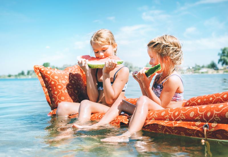 Kinder essen Wassermelone im Wasser